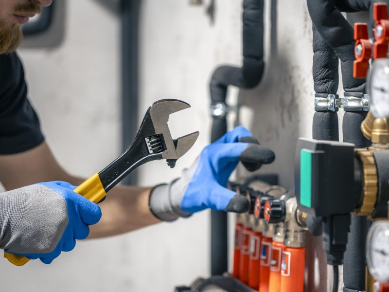 man-installs-heating-system-house-checks-pipes-with-wrench